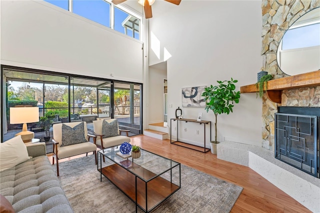 living area with plenty of natural light, a fireplace, ceiling fan, and wood finished floors