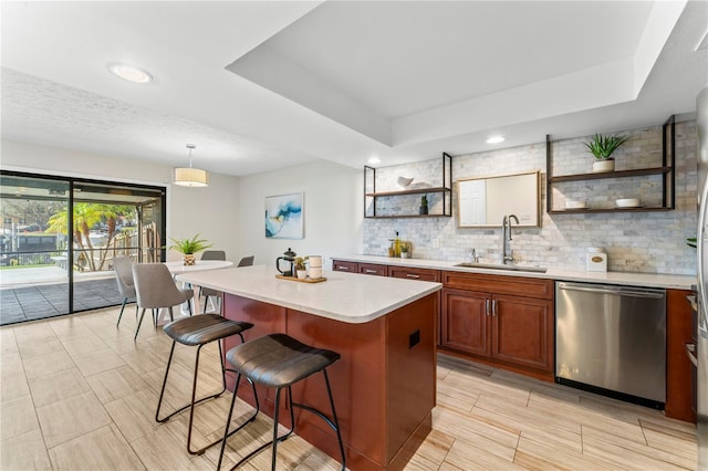 kitchen with a raised ceiling, light countertops, stainless steel dishwasher, open shelves, and a sink