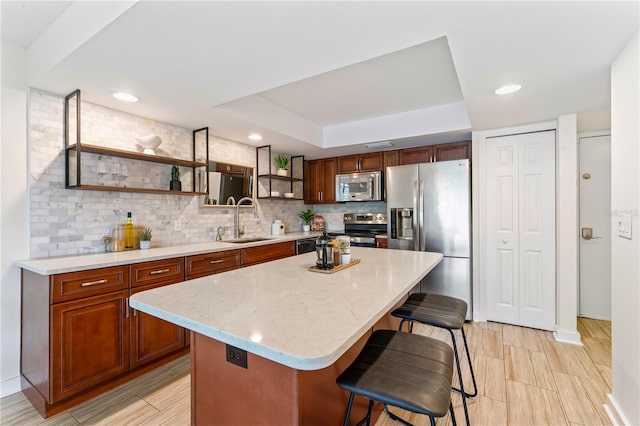 kitchen with a sink, a kitchen breakfast bar, appliances with stainless steel finishes, open shelves, and tasteful backsplash