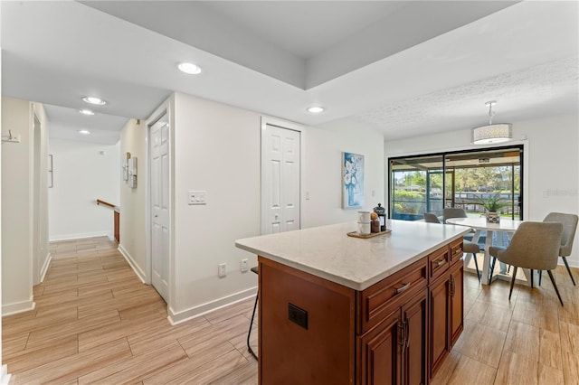 kitchen with a breakfast bar area, recessed lighting, wood finish floors, baseboards, and decorative light fixtures