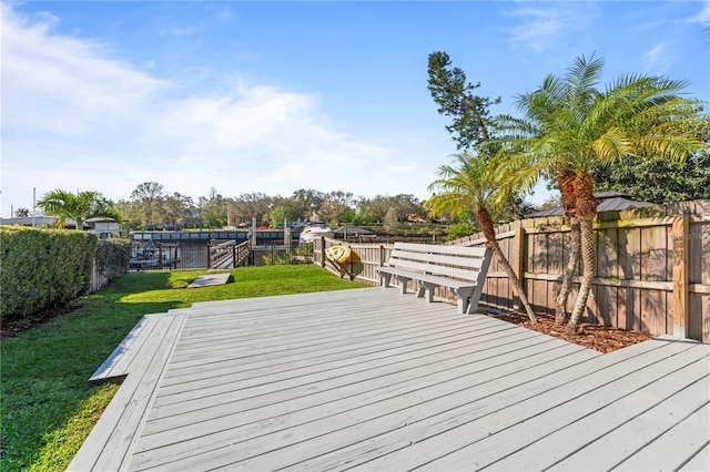 wooden terrace with a lawn, a fenced backyard, and a dock