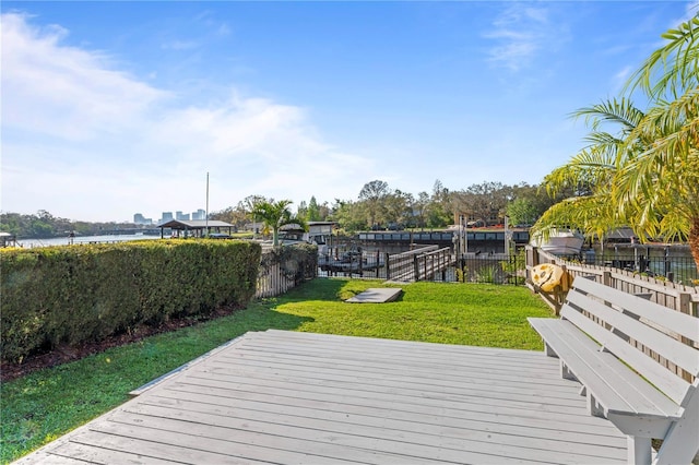 deck with a yard, a dock, a water view, and fence