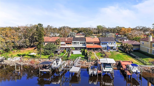 dock area featuring a water view, boat lift, a residential view, and a lawn