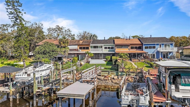 dock area with a residential view, a water view, a lawn, and boat lift