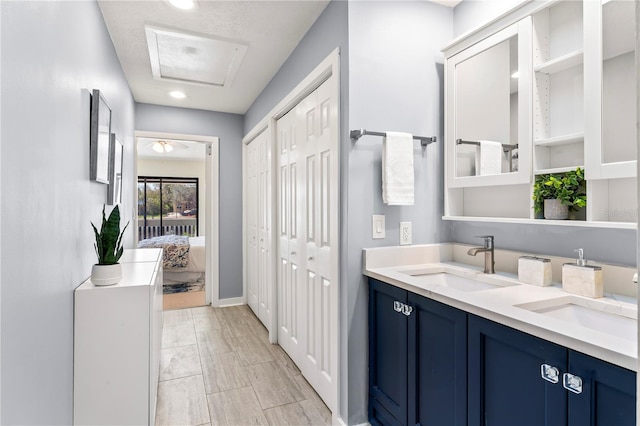 bathroom featuring ensuite bathroom, double vanity, a sink, and baseboards