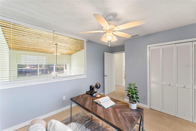 office area with ceiling fan, a textured ceiling, carpet floors, visible vents, and baseboards