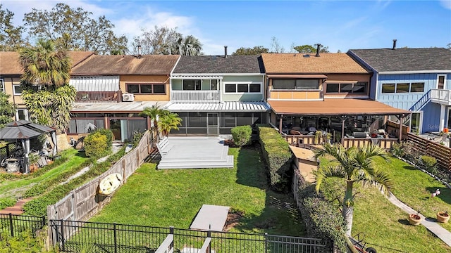 back of house featuring a gazebo, a sunroom, a fenced backyard, and a yard