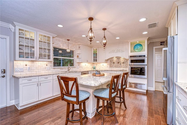 kitchen featuring a warming drawer, tasteful backsplash, a sink, and white cabinetry