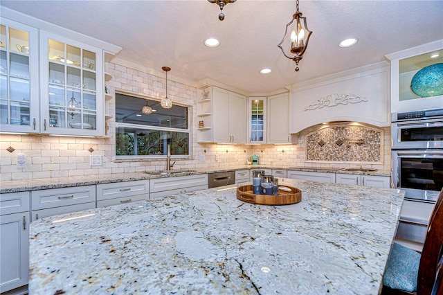 kitchen featuring stainless steel double oven, a sink, white cabinetry, tasteful backsplash, and decorative light fixtures