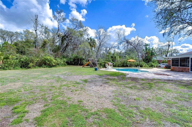 view of yard featuring a playground, a sunroom, and an outdoor pool