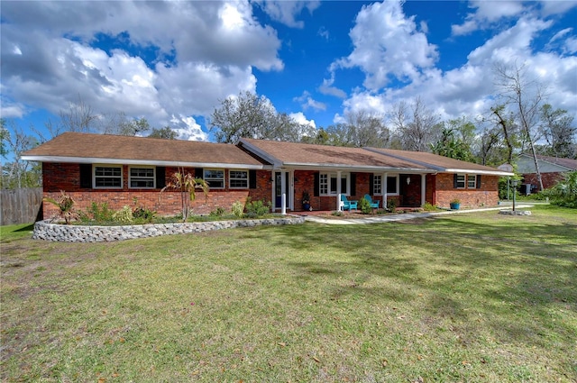 view of front of property featuring brick siding, fence, and a front lawn