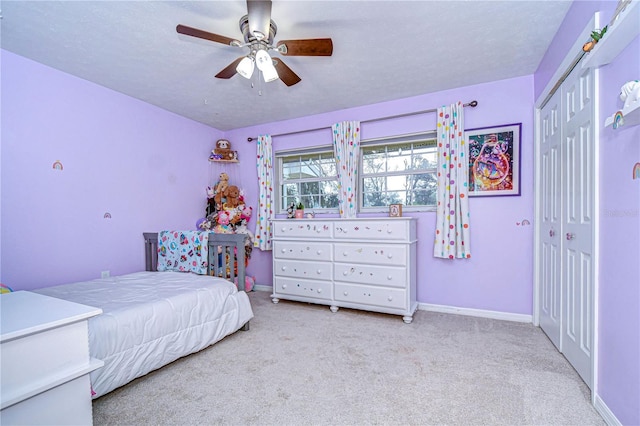 carpeted bedroom featuring ceiling fan, a closet, a textured ceiling, and baseboards