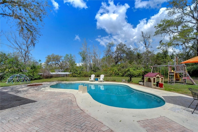 outdoor pool with a patio area, a lawn, and a playground