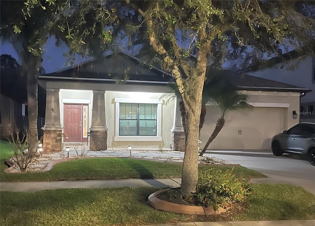 view of front of property with driveway, stone siding, an attached garage, and stucco siding