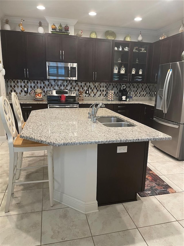 kitchen with glass insert cabinets, a sink, stainless steel appliances, crown molding, and backsplash