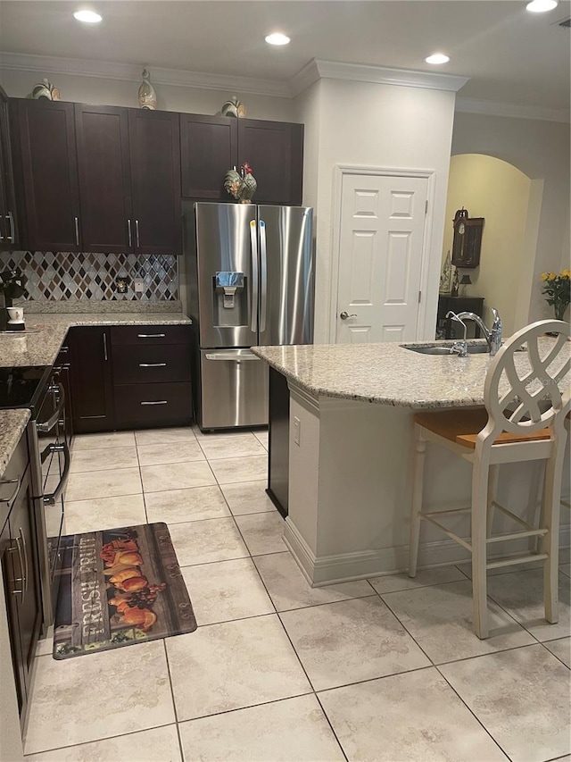 kitchen featuring light stone counters, decorative backsplash, appliances with stainless steel finishes, ornamental molding, and a sink