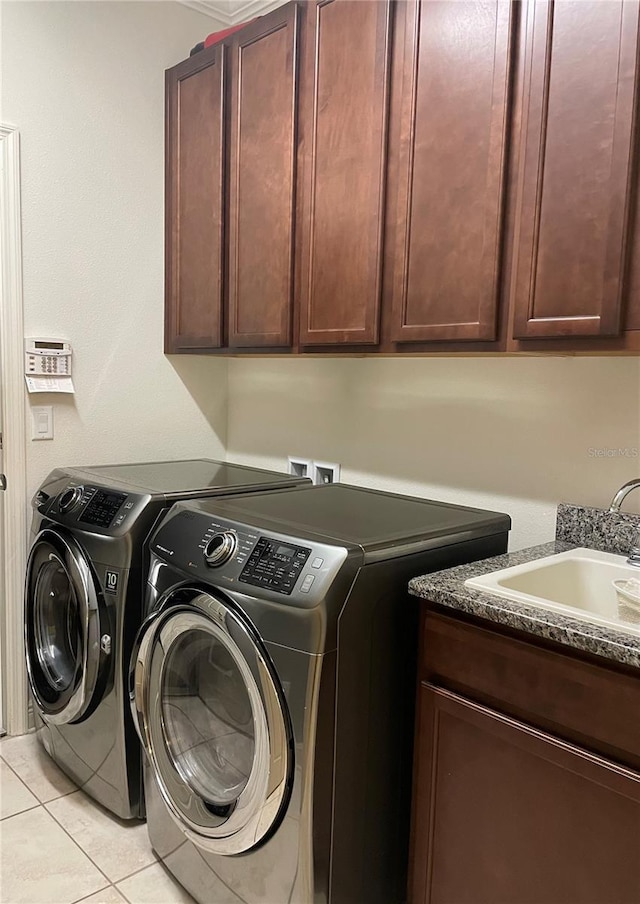 clothes washing area featuring a sink, cabinet space, light tile patterned floors, and washer and dryer