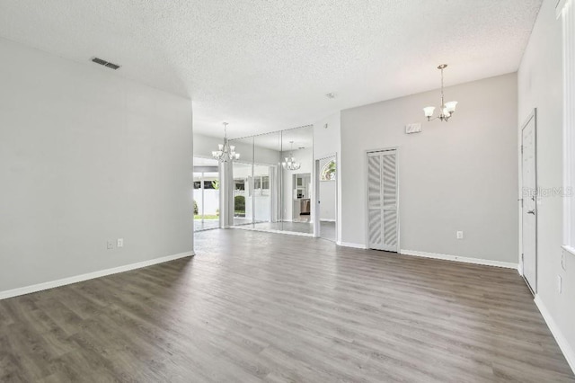 915 Brittany Park Blvd, Tarpon Springs, FL 34689 - unfurnished living room with a chandelier, a textured ceiling, wood finished floors, and baseboards