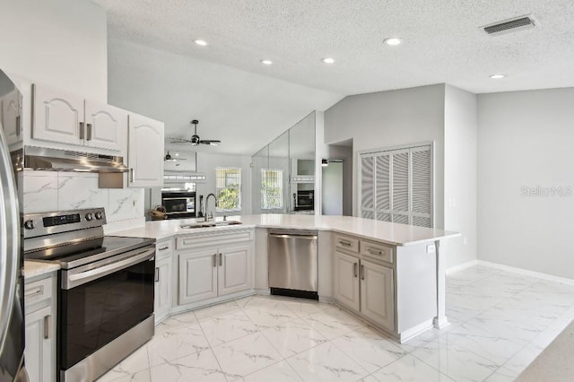 915 Brittany Park Blvd, Tarpon Springs, FL 34689 - kitchen with appliances with stainless steel finishes, under cabinet range hood, a sink, light marble finish floors, and a peninsula