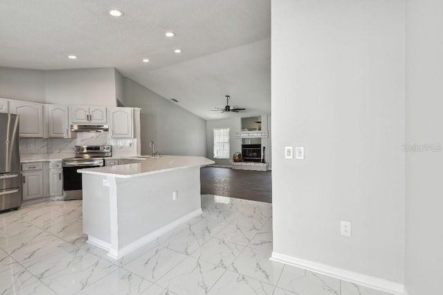 915 Brittany Park Blvd, Tarpon Springs, FL 34689 - kitchen featuring stainless steel appliances, under cabinet range hood, a sink, light marble finish floors, and vaulted ceiling