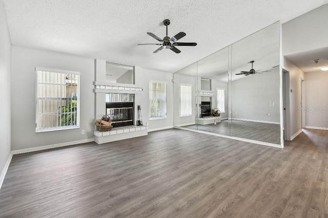 915 Brittany Park Blvd, Tarpon Springs, FL 34689 - unfurnished living room with a glass covered fireplace, a ceiling fan, a textured ceiling, baseboards, and lofted ceiling