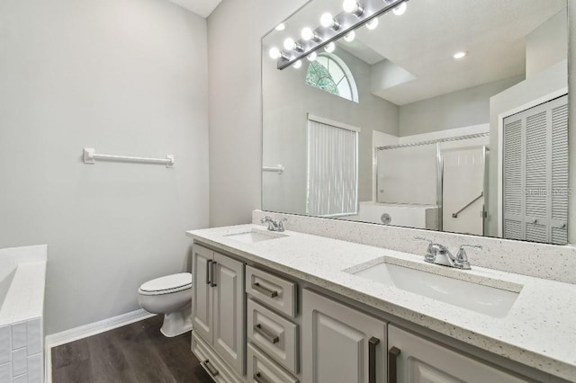 915 Brittany Park Blvd, Tarpon Springs, FL 34689 - bathroom with double vanity, toilet, an enclosed shower, wood finished floors, and baseboards