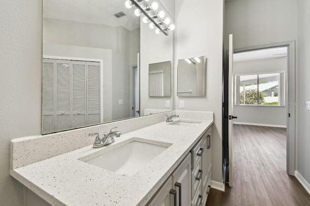915 Brittany Park Blvd, Tarpon Springs, FL 34689 - bathroom with double vanity, wood finished floors, and baseboards
