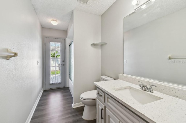 915 Brittany Park Blvd, Tarpon Springs, FL 34689 - bathroom with toilet, vanity, a textured ceiling, wood finished floors, and bathing tub / shower combination