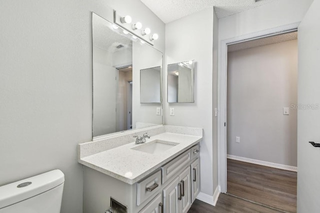915 Brittany Park Blvd, Tarpon Springs, FL 34689 - bathroom with toilet, vanity, wood finished floors, a textured ceiling, and baseboards