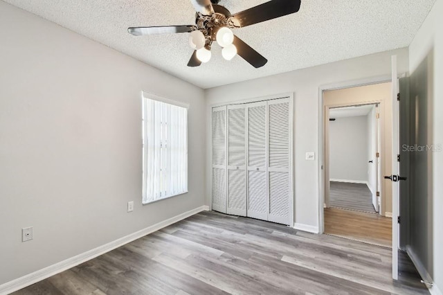 915 Brittany Park Blvd, Tarpon Springs, FL 34689 - unfurnished bedroom with a closet, a textured ceiling, wood finished floors, baseboards, and ceiling fan