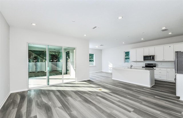 kitchen with backsplash, appliances with stainless steel finishes, open floor plan, a sink, and wood finished floors