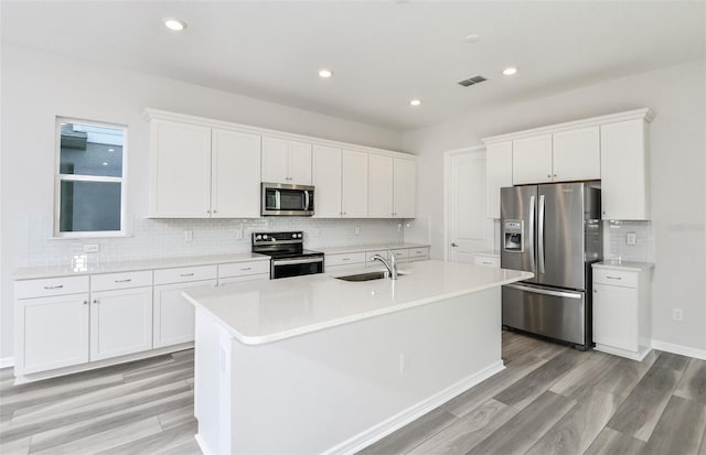 kitchen with appliances with stainless steel finishes, an island with sink, visible vents, and white cabinets