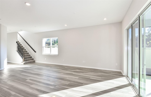 spare room featuring light wood-style floors, baseboards, stairway, and recessed lighting