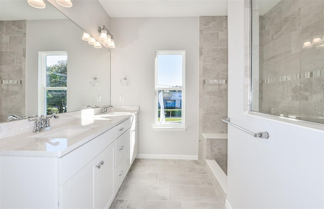 full bath featuring double vanity, walk in shower, a sink, and baseboards