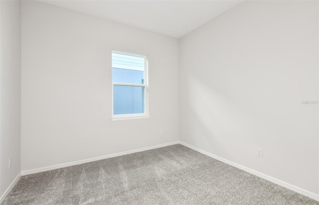 carpeted spare room featuring baseboards