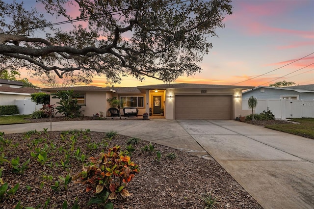 view of front of house featuring concrete driveway, an attached garage, fence, and stucco siding