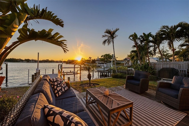 view of patio with fence, a boat dock, an outdoor living space, a water view, and boat lift