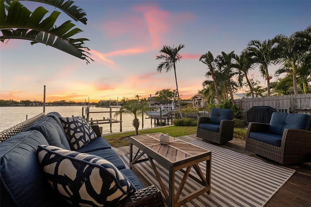 deck at dusk featuring outdoor lounge area, boat lift, fence, and a boat dock