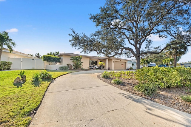 ranch-style house with a gate, fence, stucco siding, concrete driveway, and a front lawn