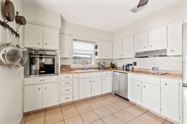 kitchen with a sink, decorative backsplash, light countertops, under cabinet range hood, and appliances with stainless steel finishes