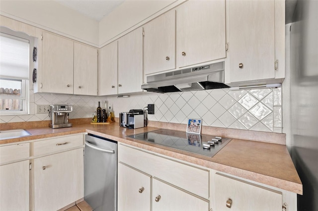 kitchen featuring a sink, decorative backsplash, light countertops, under cabinet range hood, and black electric stovetop