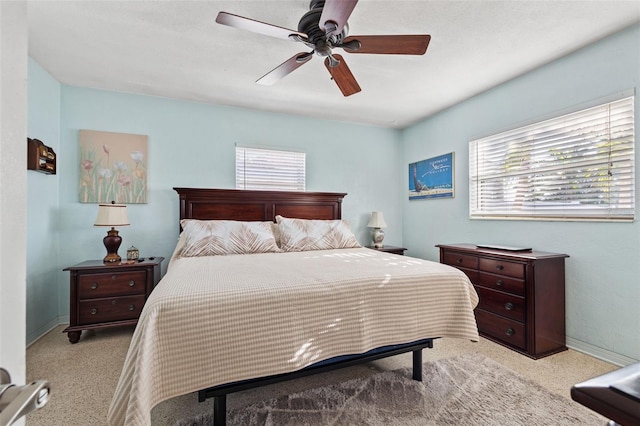 bedroom with a ceiling fan, baseboards, and light carpet