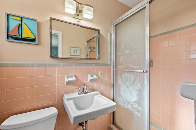 bathroom featuring a sink, toilet, and a shower stall