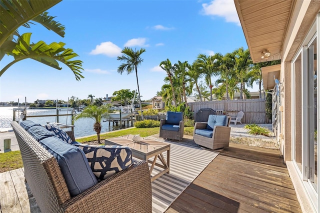 wooden terrace with a water view, a boat dock, and fence