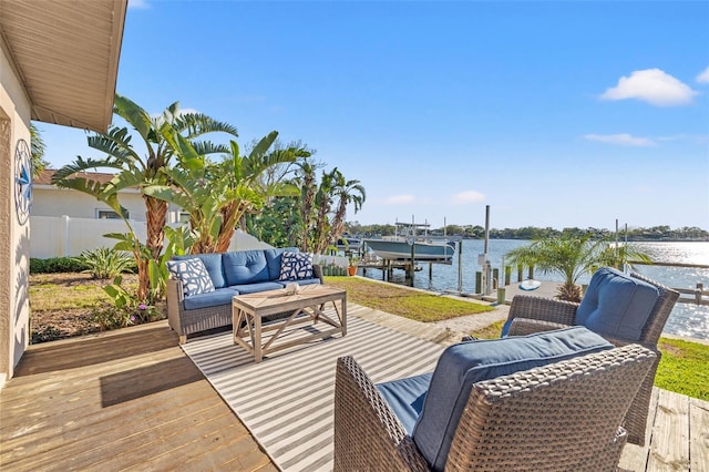 deck featuring a water view, a dock, fence, an outdoor hangout area, and boat lift