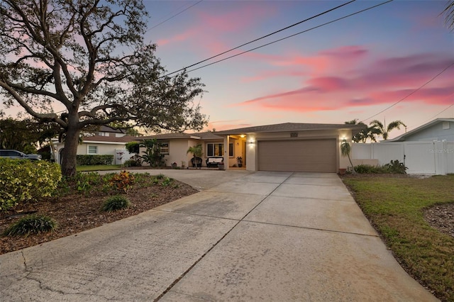 view of front of house with stucco siding, driveway, an attached garage, and fence