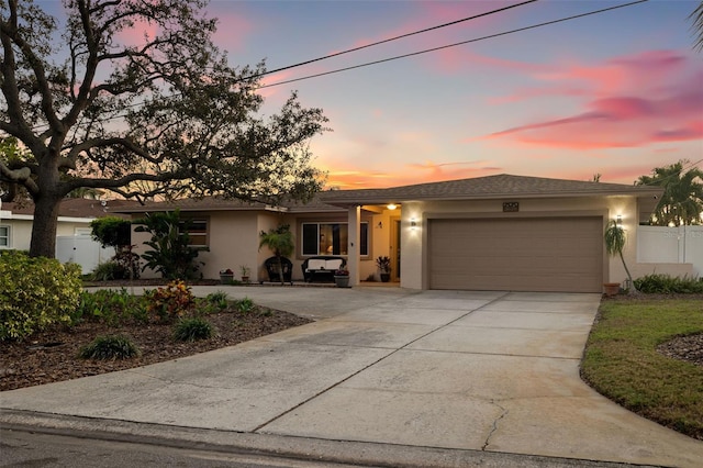 view of front of property with stucco siding, an attached garage, driveway, and fence