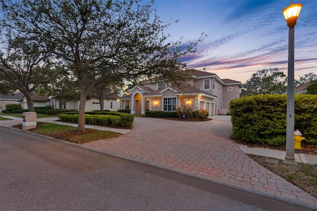 view of front of home featuring a tile roof, decorative driveway, and stucco siding