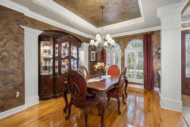 dining space with a raised ceiling, visible vents, ornate columns, and wood finished floors