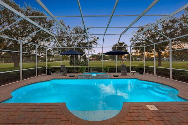 pool at dusk with glass enclosure, an outdoor pool, a patio, and an in ground hot tub